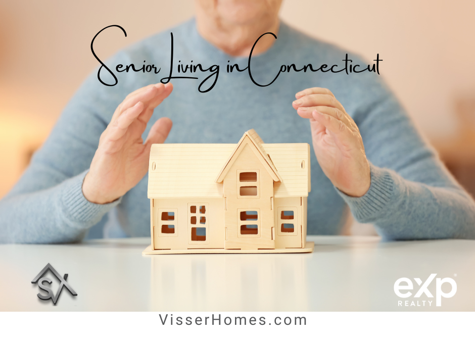 image of older woman in blue sweater with hands encompassing a toy size replica of a cape style house.